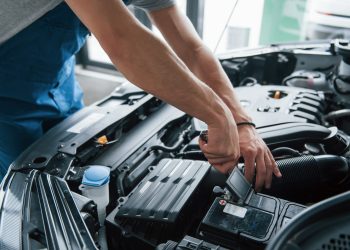 Some electronic parts. Process of repairing car after accident. Man working with engine under the hood.